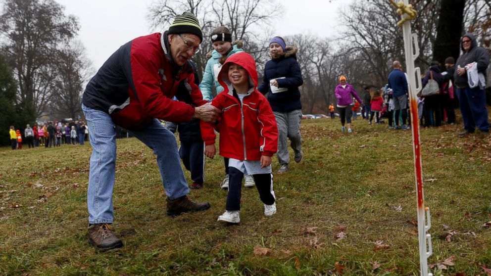 PHOTO: From left, Jim Loria, of Swartz Creek, helps Gabriel Riley, 4, of Burton, to the finish line during the 60th annual Thanksgiving Day Turkey Trot on Thursday, Nov. 24, 2016, at Mott Park in Flint, Mich.