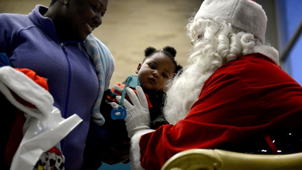 PHOTO: Kylan Pouncil, 10 months,  is passed to Santa Claus as members of the community gather for a tree lighting on Dec. 2, 2016 in Flint, Mich. 