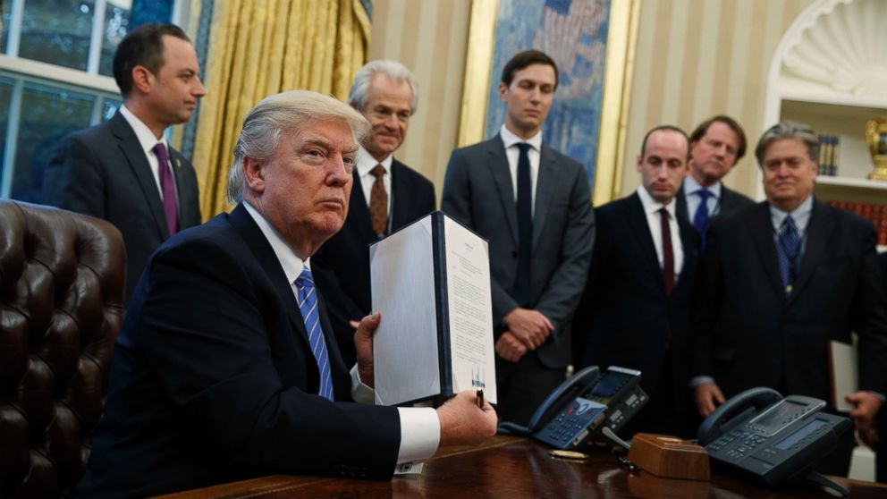 President Donald Trump shows off a signed executive order to reinstate a policy barring any recipient of U.S. assistance from performing or promoting abortions abroad with money they receive from non-U.S. sources, Jan. 23, 2017, in the Oval Office of the White House in Washington. 