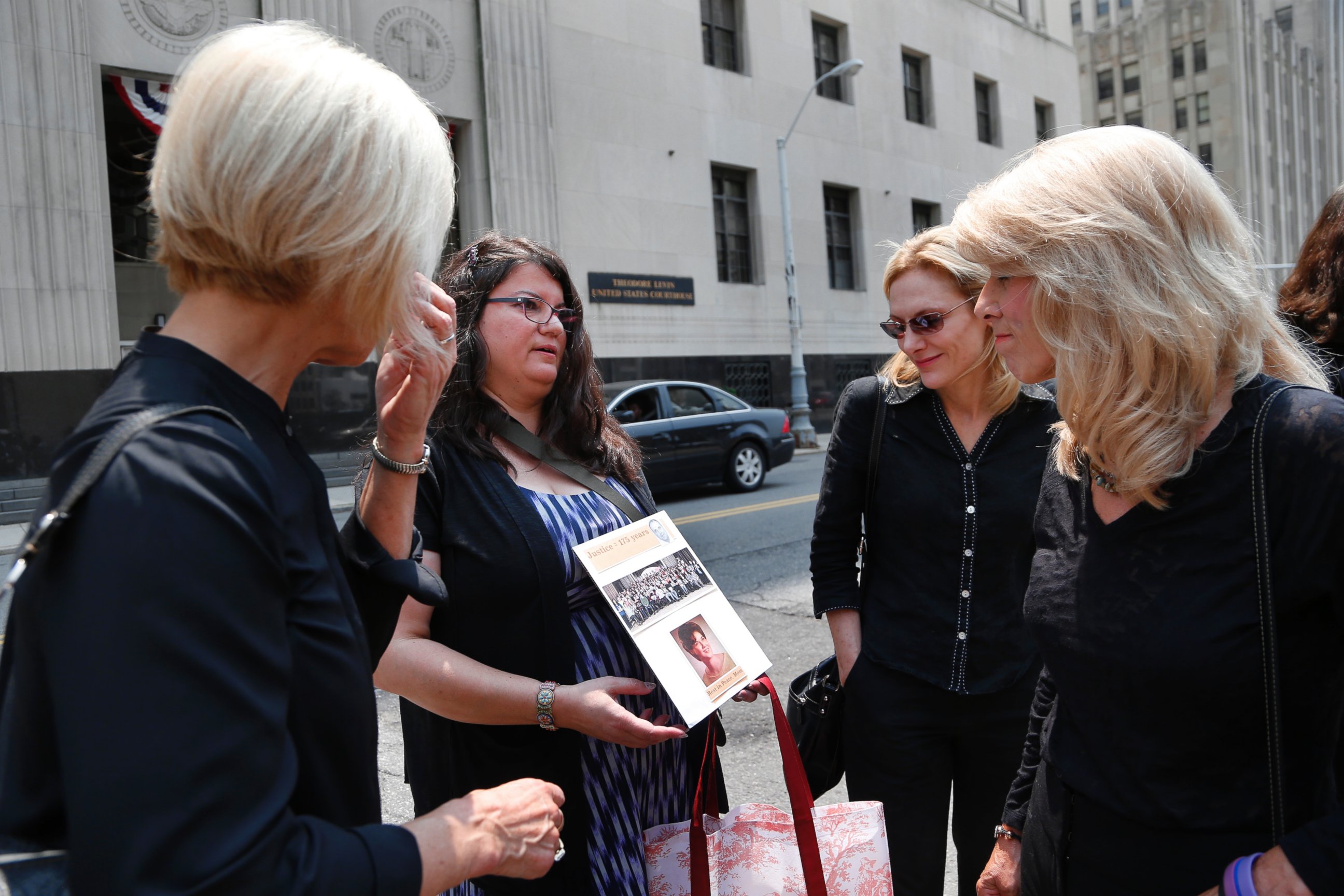 PHOTO: Liz Lupo, second from left, shows a sign in honor of her mother, Marianne Lupo, a former patient of Dr. Farid Fata, outside federal court, Monday, July 6, 2015, in Detroit. 