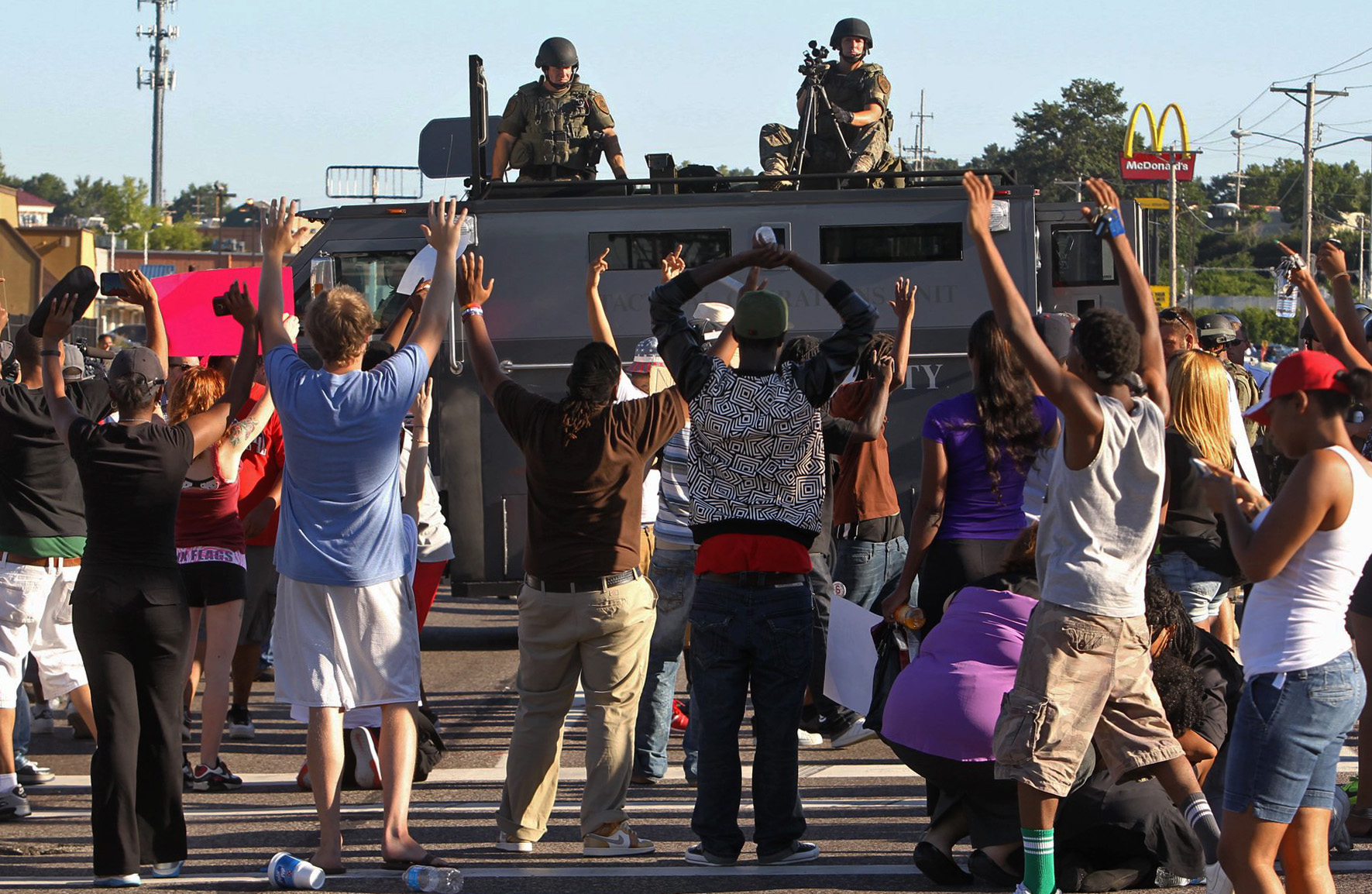 PHOTO: Protesters raise their hands in front of police atop an armored vehicle in Ferguson, Mo. on Aug. 13, 2014. 