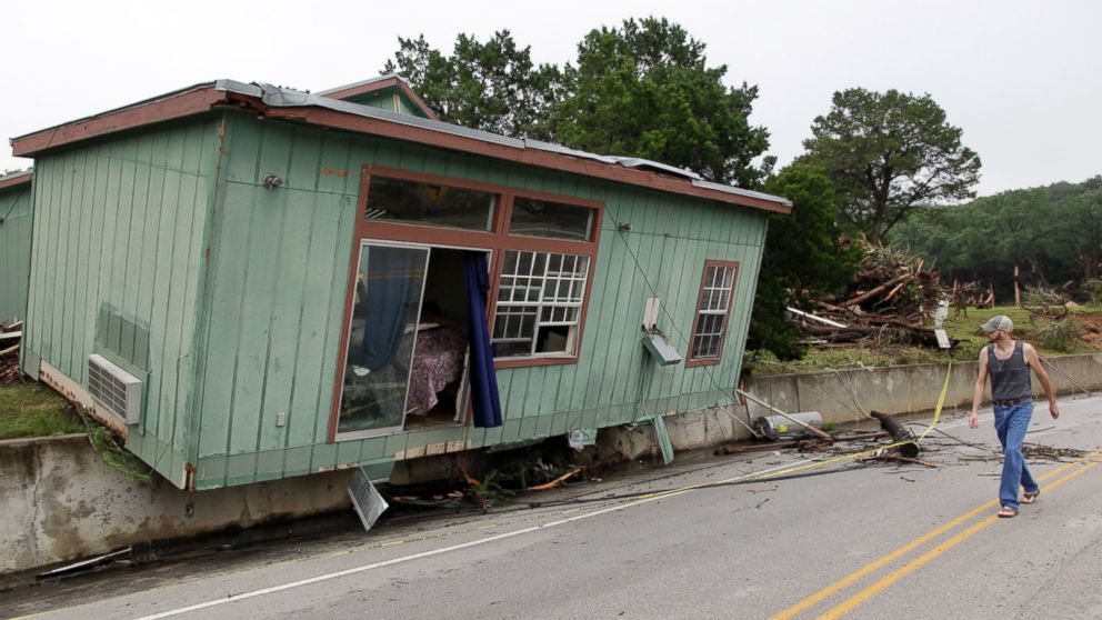 A man walks past a cabin that was torn from its foundation in a flood on the Blanco River days earlier, May 26, 2015, in Wimberley, Texas.