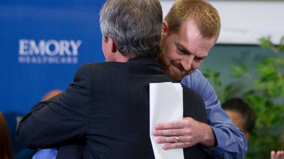 Ebola victim Dr. Kent Brantly, right, hugs a member of the medical staff that treated him, after being released from Emory University Hospital, Aug. 21, 2014, in Atlanta. 