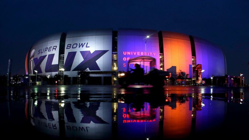Workers drive past the University of Phoenix Stadium, Jan. 29, 2015, in Glendale, Ariz. 