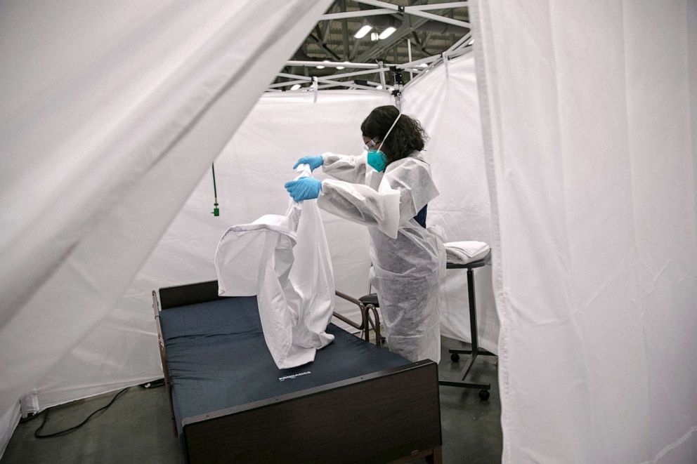 PHOTO: A nurse makes a bed in a Covid-19 isolation bay at the Austin Convention Center on Aug. 7, 2020 in Austin, Texas. The cavernous facility was prepared for use as a field hospital for Covid-19 patients, if Austin hospitals were to become overwhelmed.