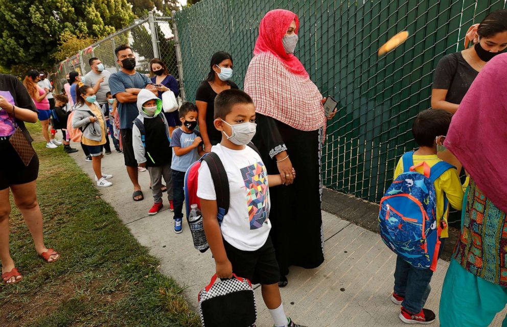 PHOTO: First Grader Ahnaf Abrar with his mother Shamima Abrar, using a QR code for health clearances on her phone, checks in at Lankershim Elementary School in North Hollywood, Calif., Aug. 17, 2021.