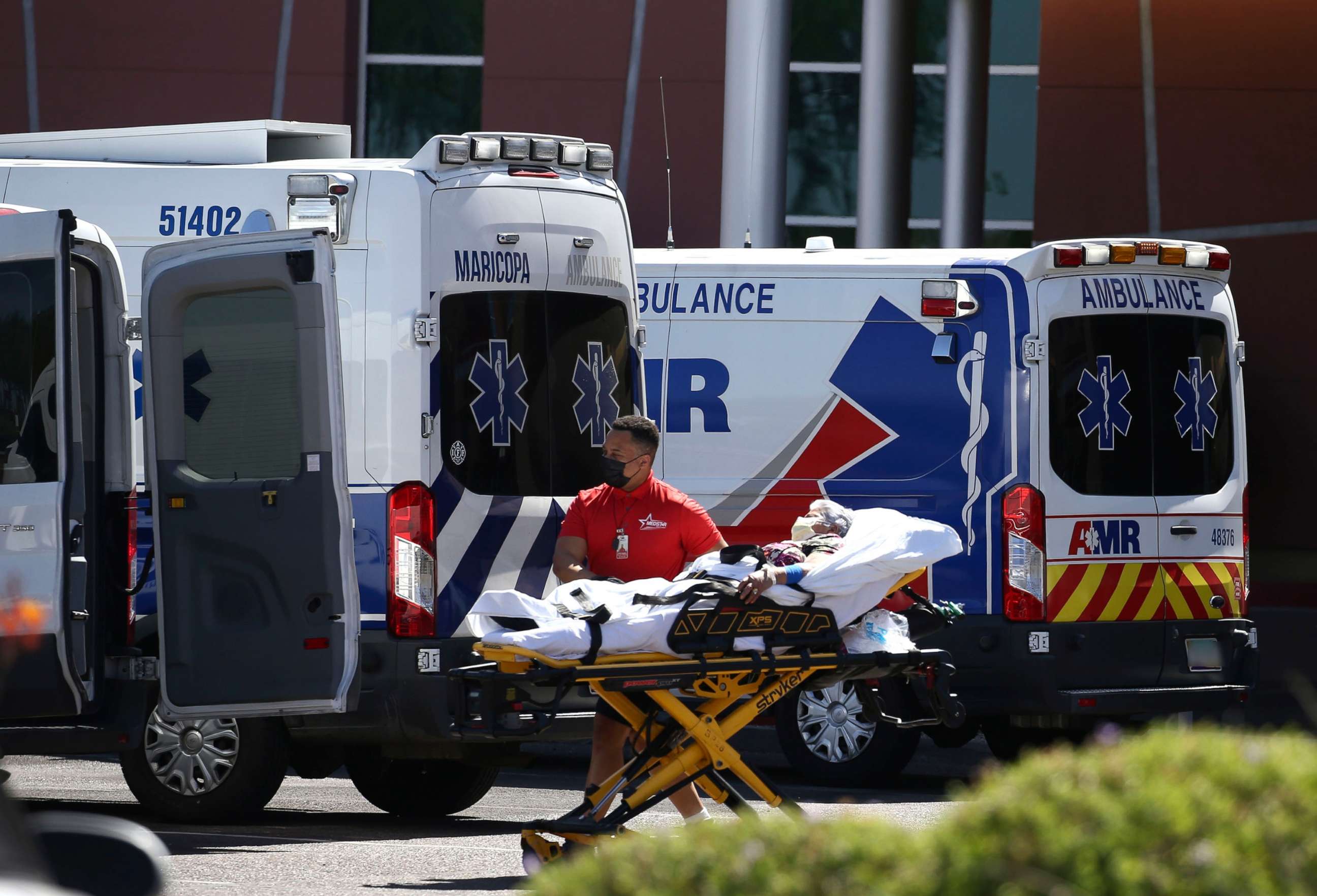 PHOTO: A person is brought to a medical transport vehicle from Banner Desert Medical Center as several transports and ambulances are shown parked outside the emergency room entrance, June 16, 2020, in Mesa, Ariz. 