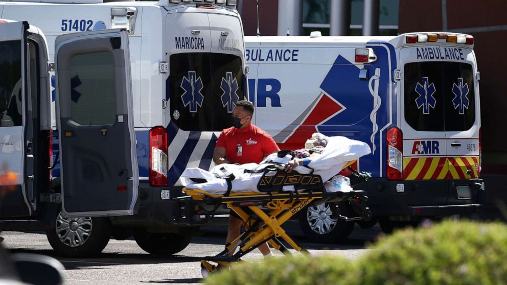 PHOTO: A person is brought to a medical transport vehicle from Banner Desert Medical Center as several transports and ambulances are shown parked outside the emergency room entrance, June 16, 2020, in Mesa, Ariz. 
