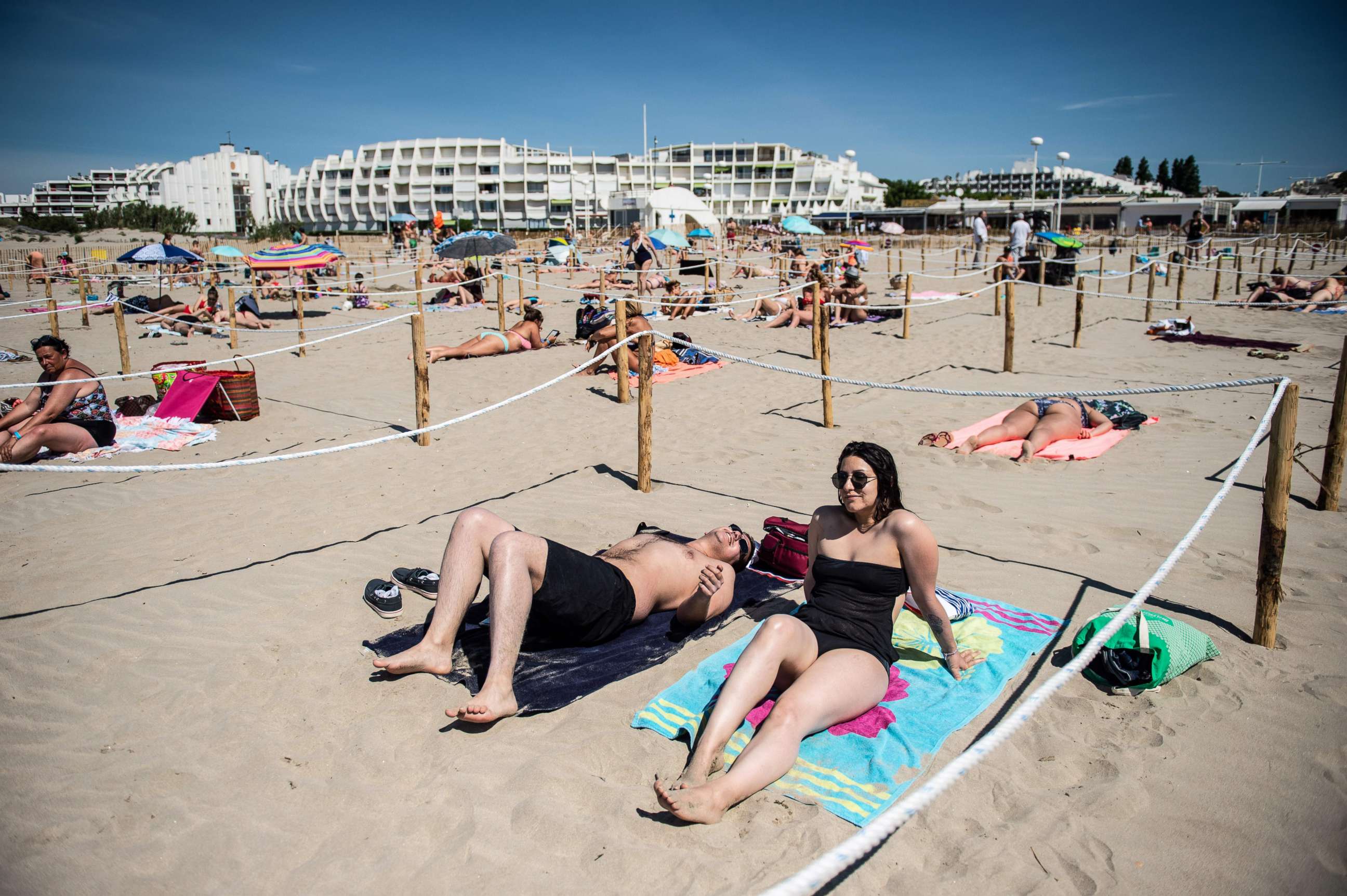 PHOTO: Two people sunbath at 'Couchant or Sunset beach', in a roped off distancing zone marked out by the municipality along the beach in La Grande Motte, southern France, on May 21, 2020.