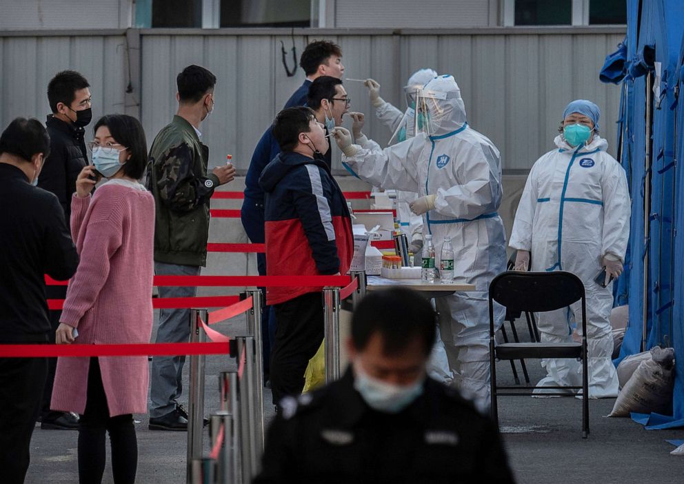 PHOTO: Health workers dressed in protective clothing give nucleic acid tests to men at a mass testing site to prevent COVID-19, March 14, 2022 in Beijing, China.