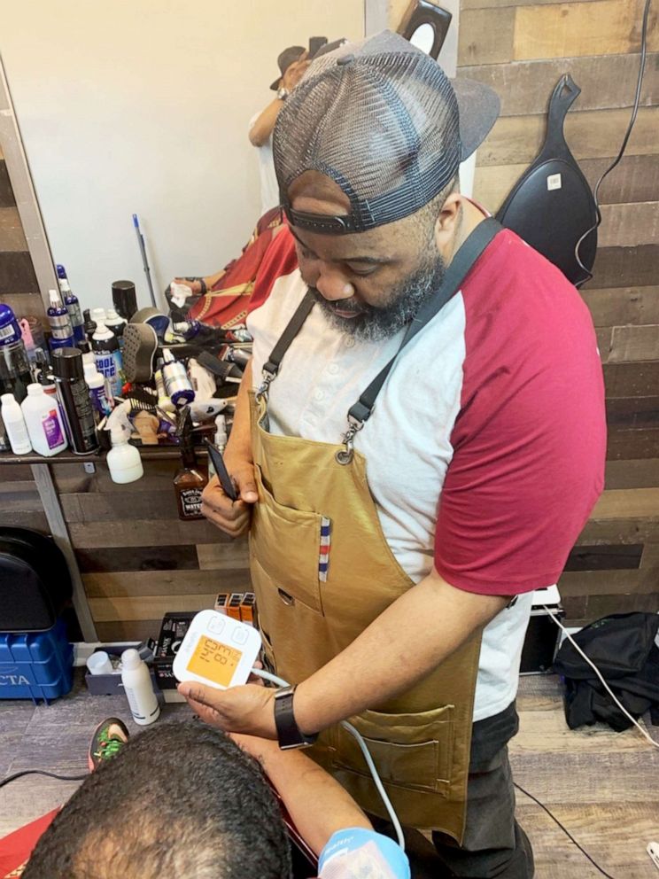 PHOTO: Barber Paul Jones takes a reading of a client's blood pressure during a regular haircut visit. Live Chair Health equips all of its affiliated barbershops with blood pressure monitors in the hopes it may save lives.