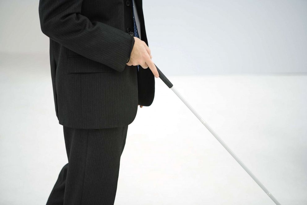 PHOTO: Blind man walks with white stick.