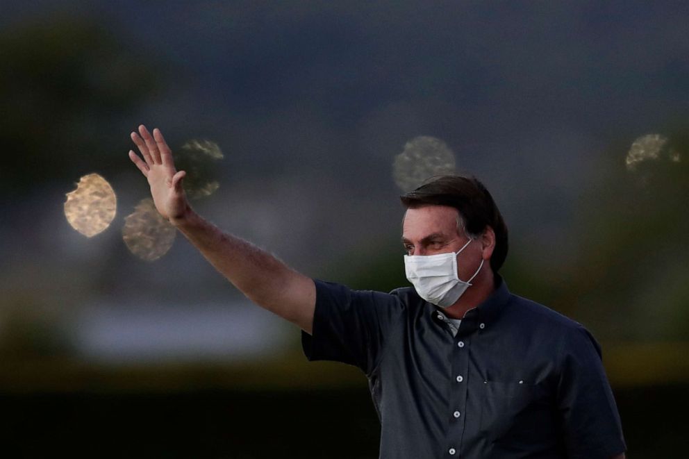 PHOTO: Brazil's President Jair Bolsonaro who is infected with COVID-19, wears a protective face mask as he waves to supporters during a Brazilian flag retreat ceremony outside his official residence the Alvorada Palace, in Brasilia, Brazil.