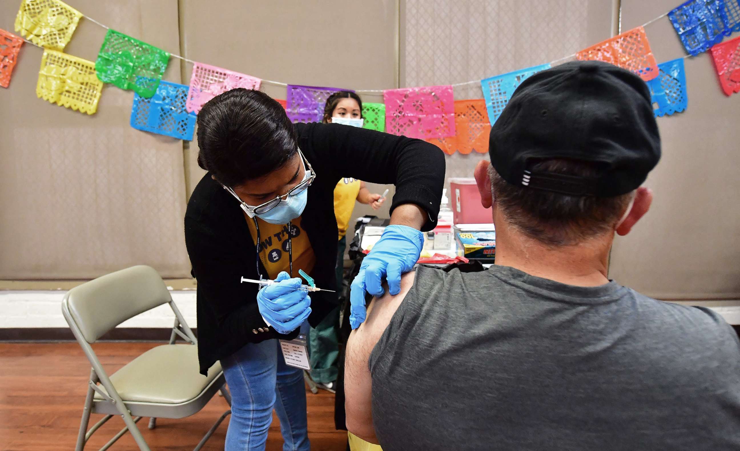 PHOTO: Registered Nurse Mariam Salaam administers the Pfizer booster shot at a Covid vaccination and testing site decorated for Cinco de Mayo at Ted Watkins Park in Los Angeles, May 5, 2022.