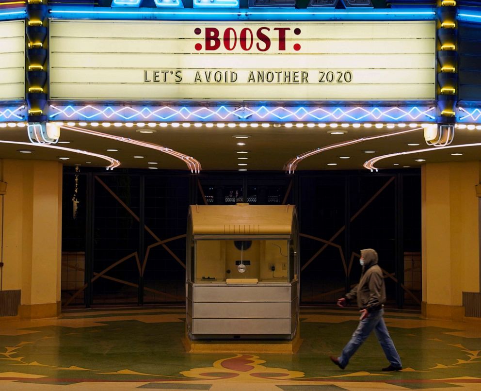 PHOTO: A man walks underneath the marquee of the Alex Theatre in Glendale, Calif., which bears a message urging people to get COVID-19 vaccine booster shots, Jan. 24, 2022.