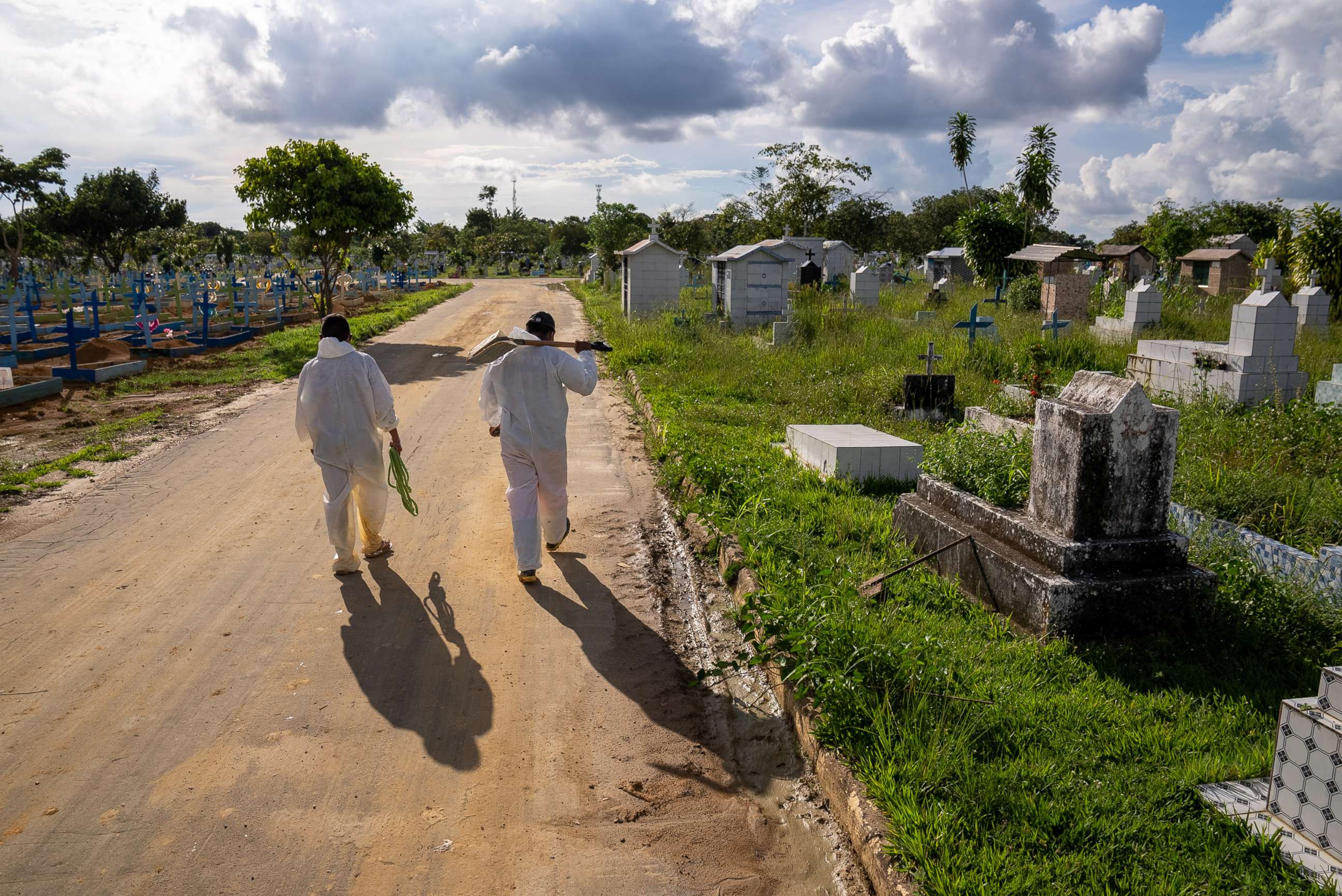 PHOTO: Grave diggers walk down a road at Nossa Senhora Aparecida public cemetery, March 30, 2021, in Manaus, Brazil.
