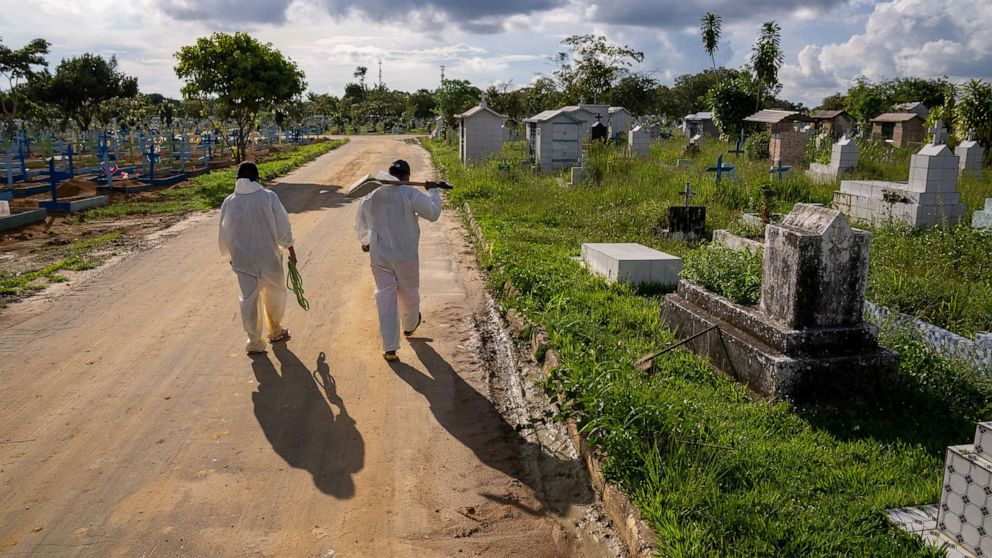 PHOTO: Grave diggers walk down a road at Nossa Senhora Aparecida public cemetery, March 30, 2021, in Manaus, Brazil.