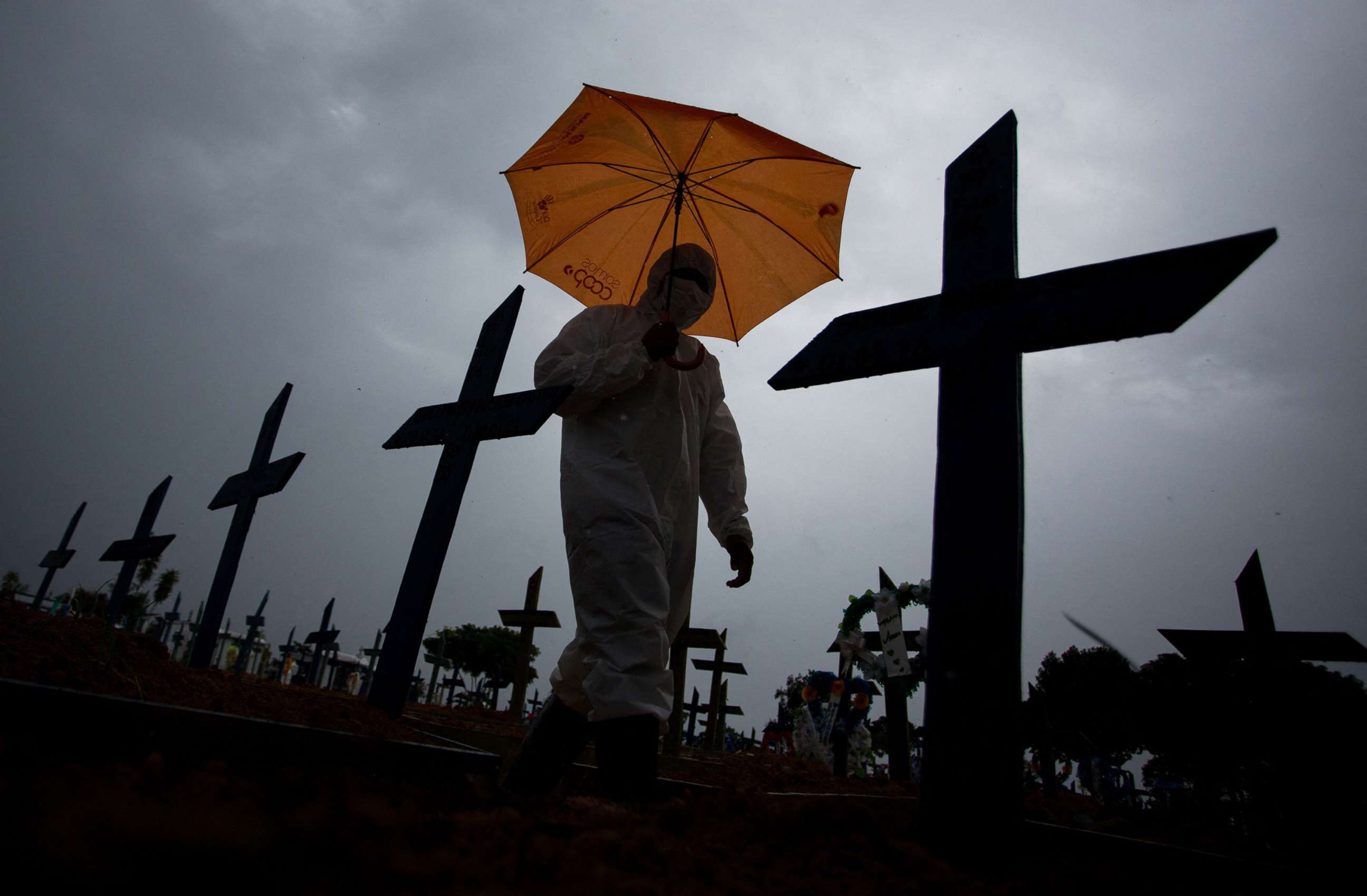 PHOTO: A worker wearing a protective suit and carrying an umbrella walks past the graves of COVID-19 victims at the Nossa Senhora Aparecida cemetery, in Manaus, Brazil, Feb. 25, 2021. 