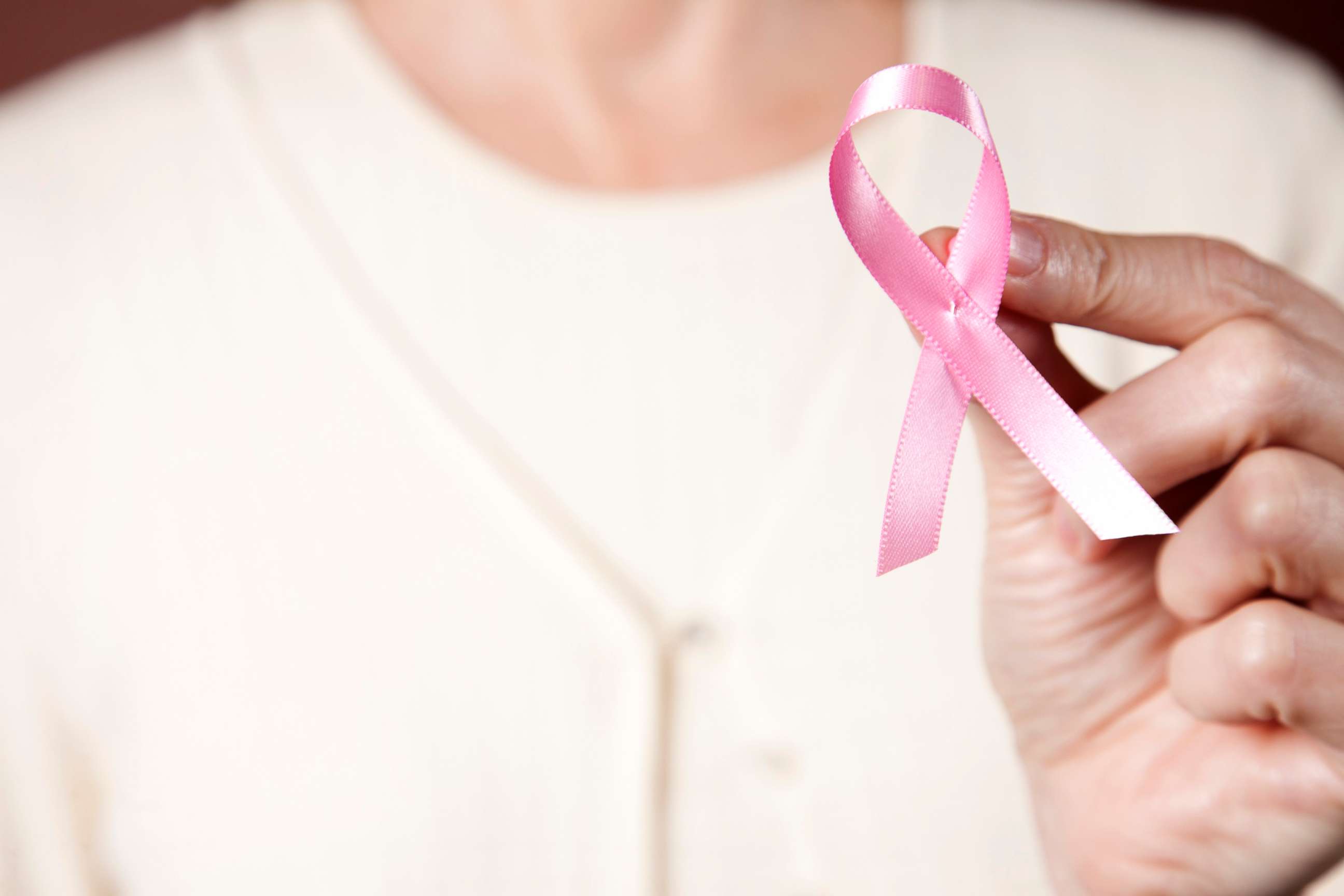 PHOTO: In this undated stock photo, a woman wearing a pink sweater holding a pink breast cancer ribbon.