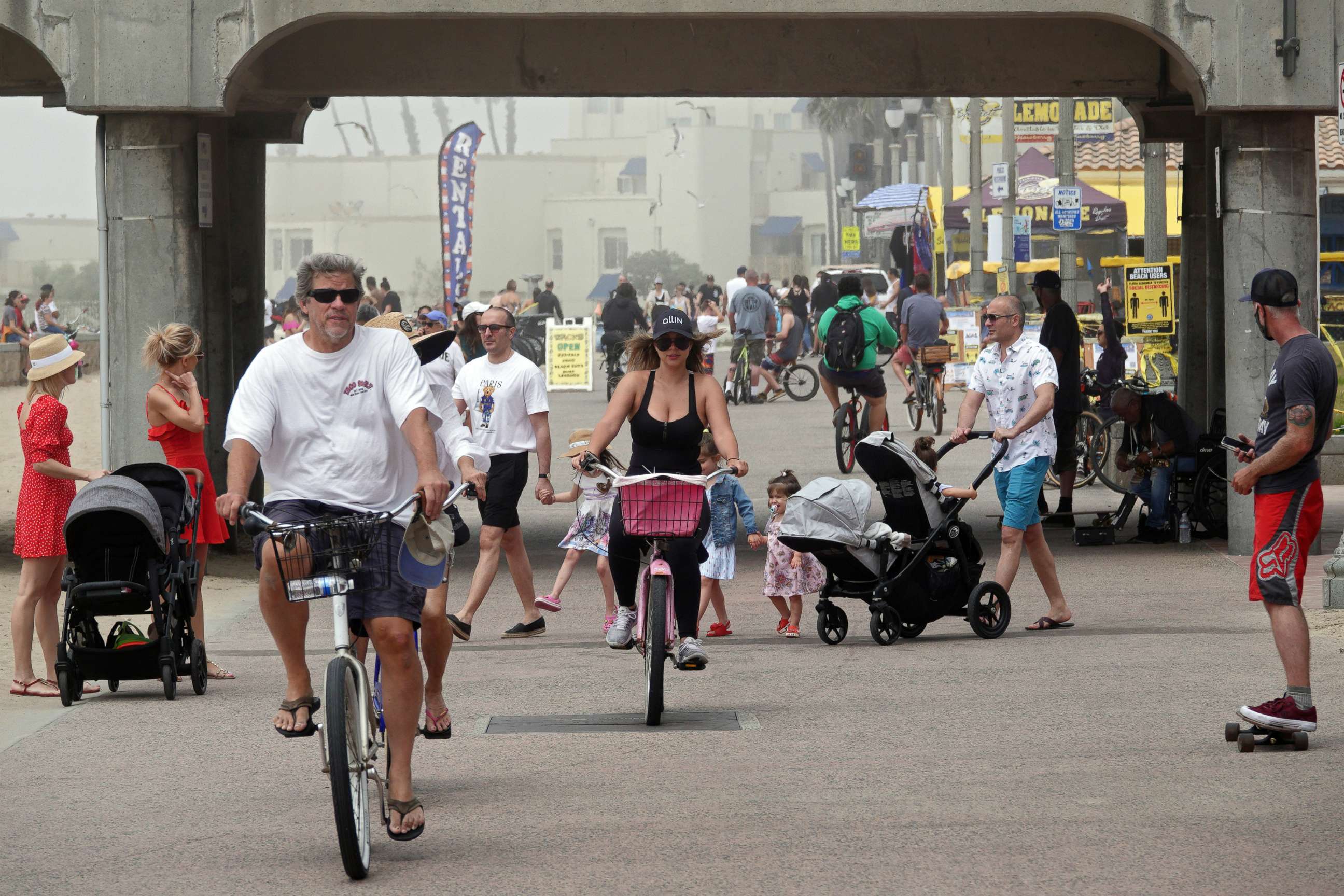 PHOTO: People ride bikes and walk on a path along the beach on April 26, 2020 in Huntington Beach, Calif.