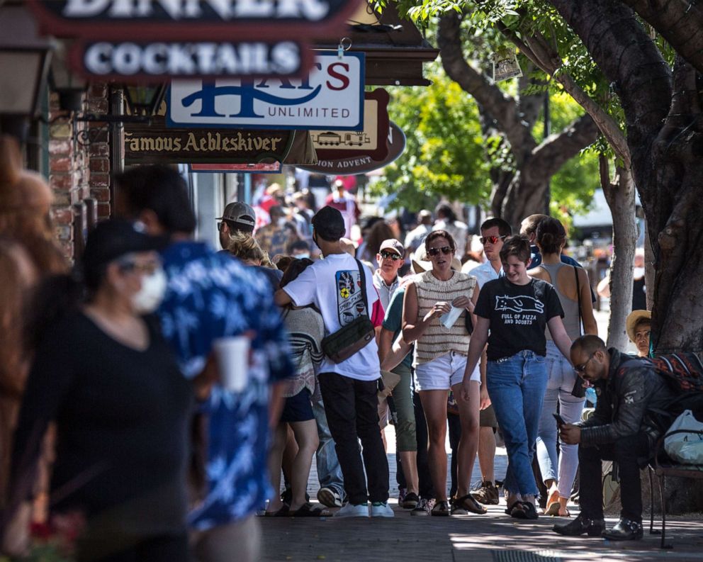 PHOTO: A crowd of people, some wearing face masks, walk through the streets of Solvang as boutique shops, tasting rooms, hotels, and restaurants reopen to visitors on June 13, 2020, in Solvang, California.