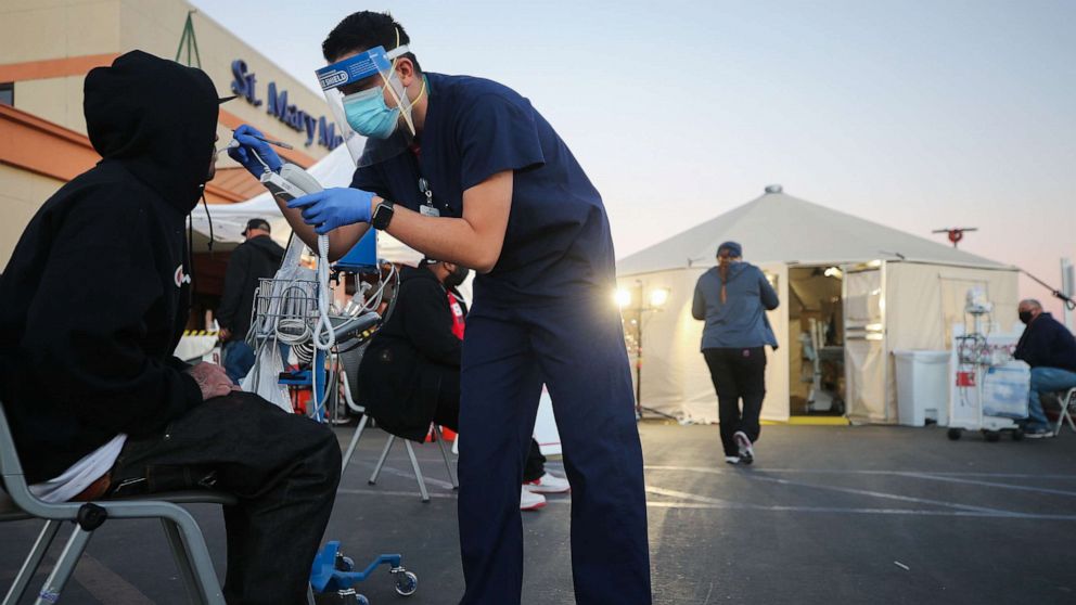 PHOTO: A California National Guard medic checks vital signs of an incoming patient in front of triage tents set up outside St Mary Medical Center amid a surge in COVID-19 patients in Southern California, Dec. 18, 2020 in Apple Valley, California.