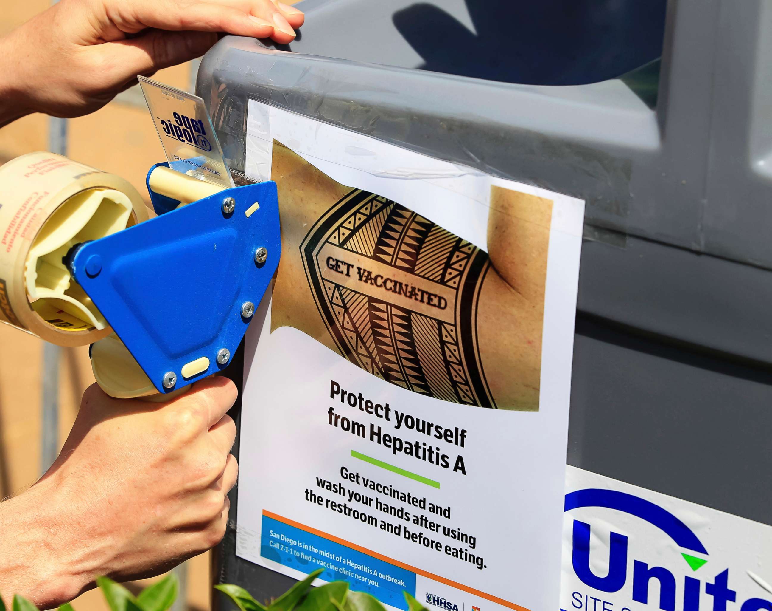 PHOTO: A worker tapes signage telling people to get vaccinated to protect themselves against hepatitis A on hand washing sinks installed at the Neil Good Day Center in downtown San Diego, Sept. 1, 2017.