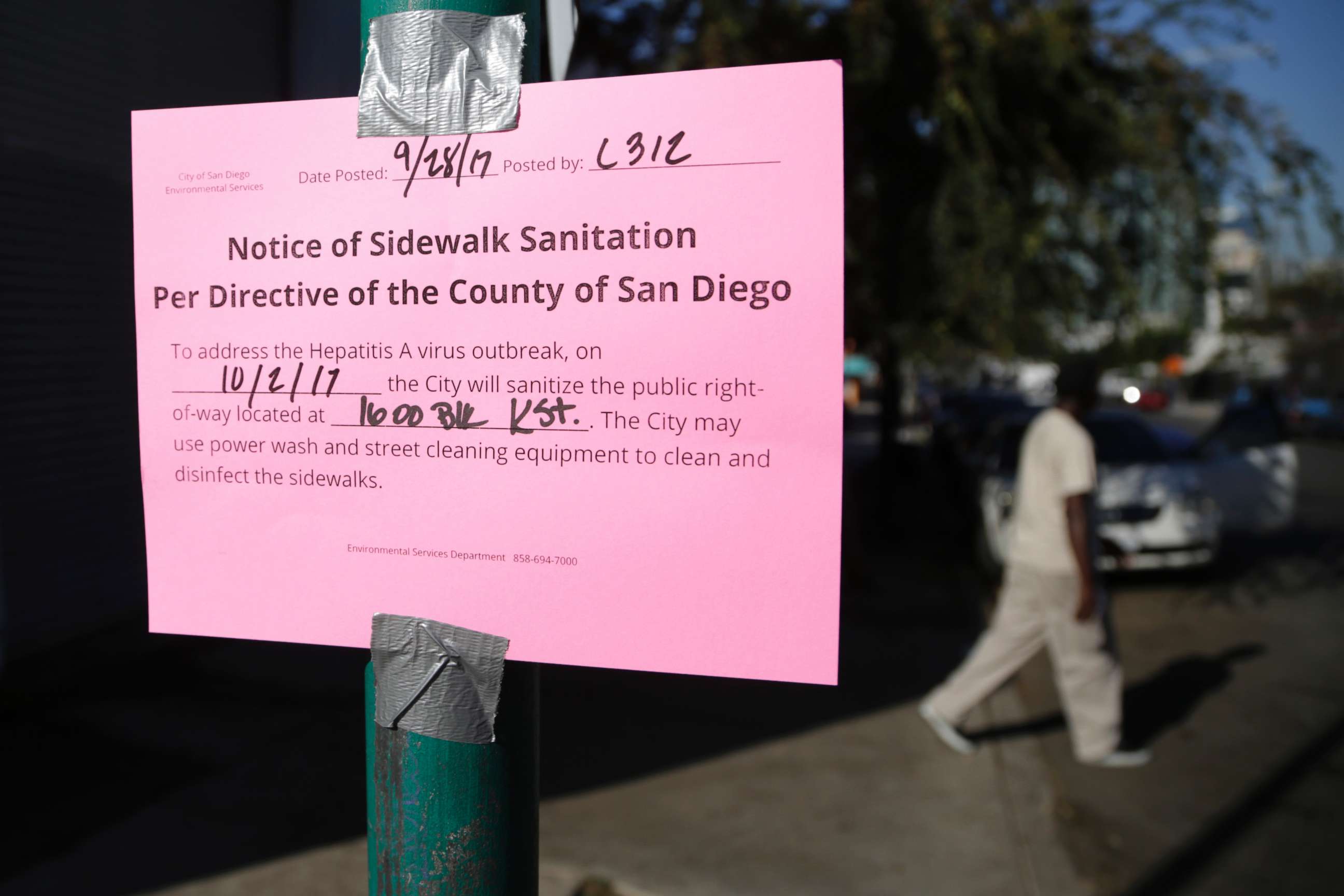 PHOTO: A man passes behind a sign warning of an upcoming street cleaning to address a hepatitis A outbreak in San Diego, Sept. 28, 2017.