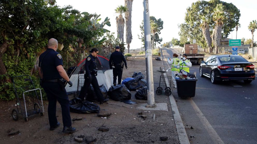 Police officers remove a tent left by the homeless during efforts to sanitize neighborhoods to control the spread of hepatitis A, in San Diego, Sept. 25, 2017.