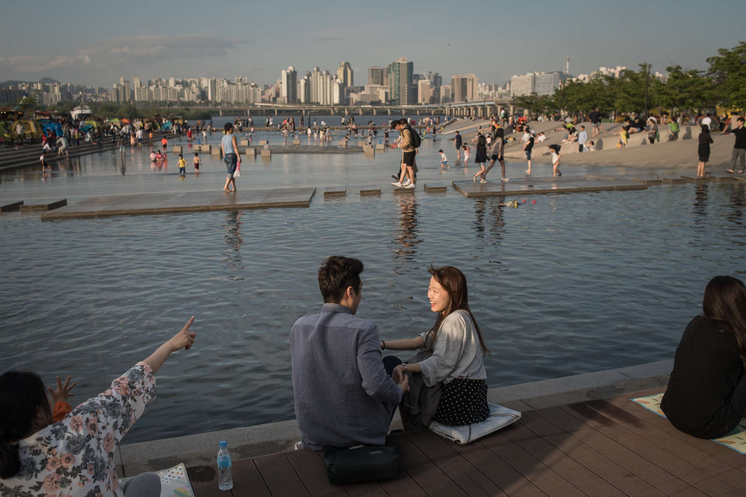 PHOTO: A young couple sits next to a water feature before the Han river and the city skyline, at Yeouido park in Seoul, May 5, 2017.