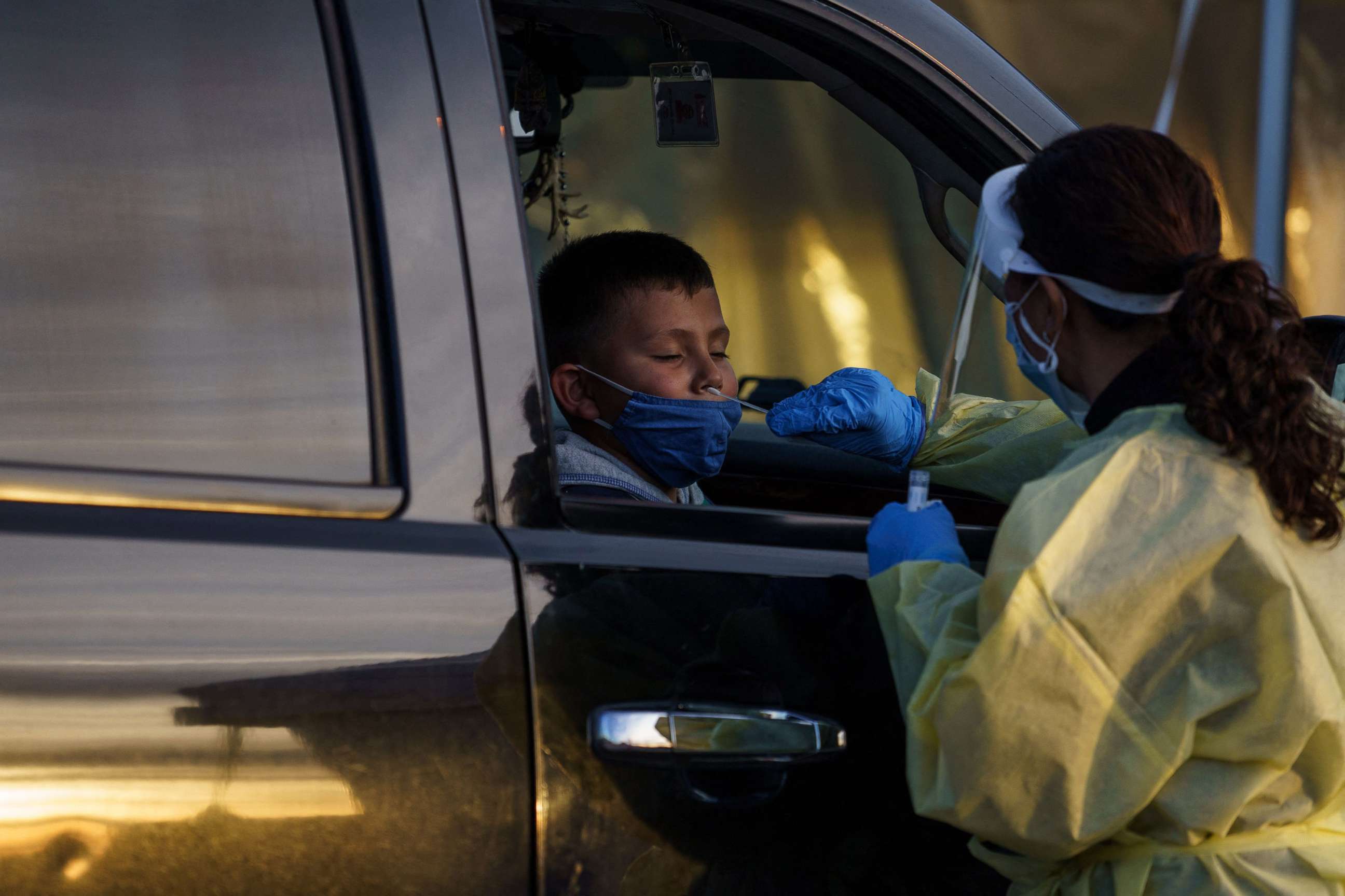 PHOTO: Healthcare worker Azucena Estrada gives five-year-old Gabriel Govea a nasal swab samples at a drive-thru COVID-19 testing site in El Paso, Texas, Jan. 12, 2022.