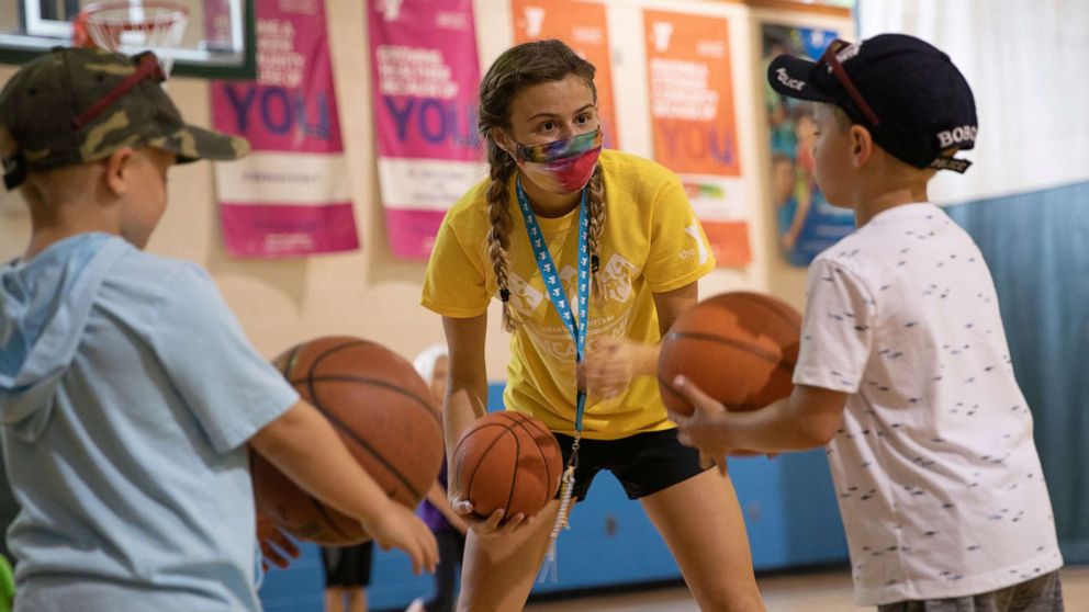 PHOTO: A counselor wearing a protective face mask plays with children as summer camps reopen amid the spread of COVID-19 at Carls Family YMCA summer camp in Milford, Mich., June 23, 2020.
