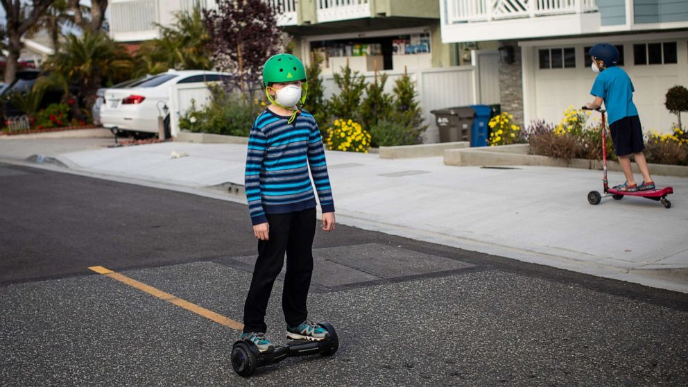 PHOTO: Children play in the streets while wearing face masks, in Redondo Beach, Calif., during the coronavirus pandemic and current safer-at-home orders from California Gov. Gavin Newsom, April 5, 2020.