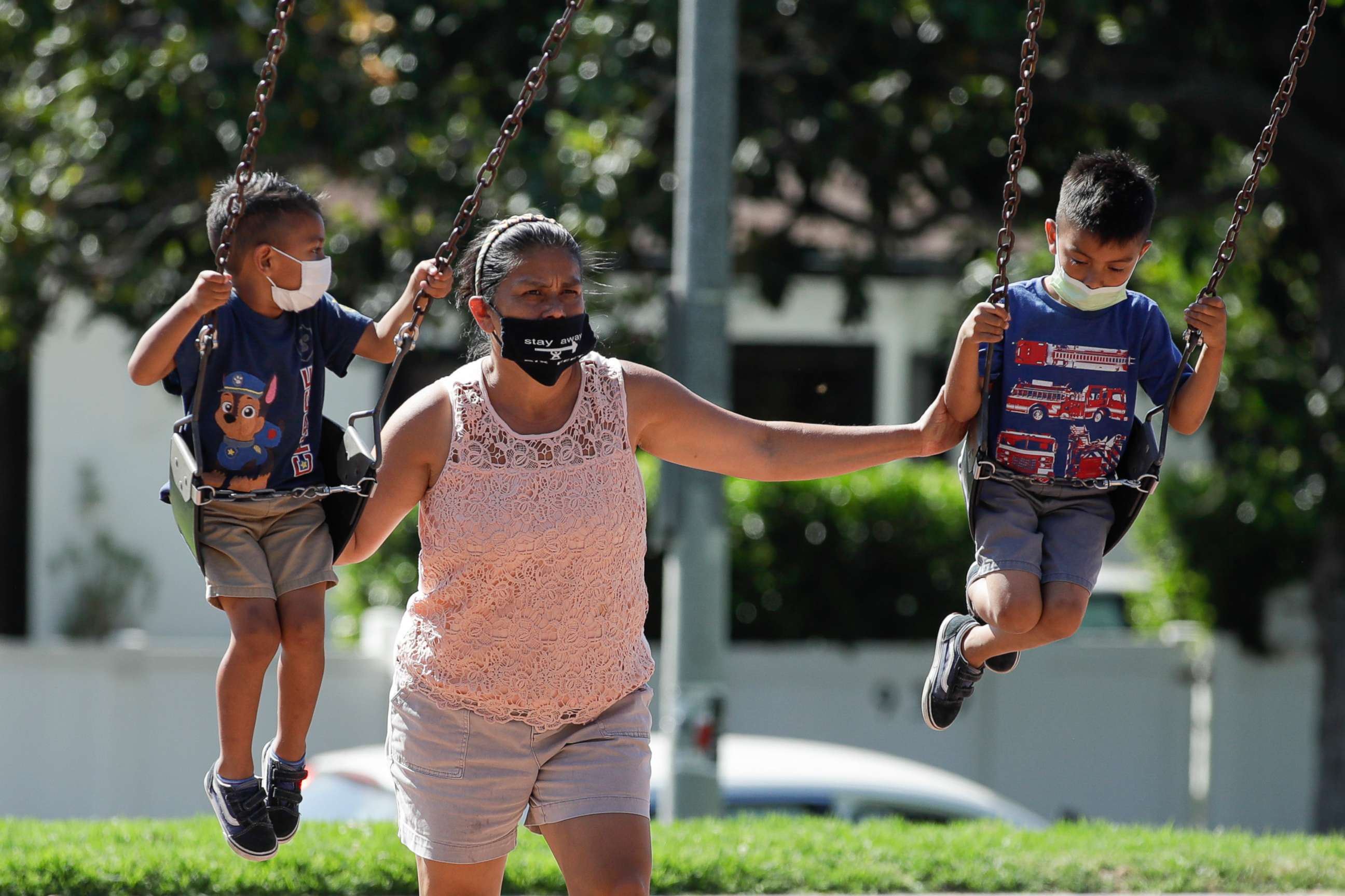 PHOTO: A woman and two children wear masks at a playground, July 11, 2020, in Los Angeles.