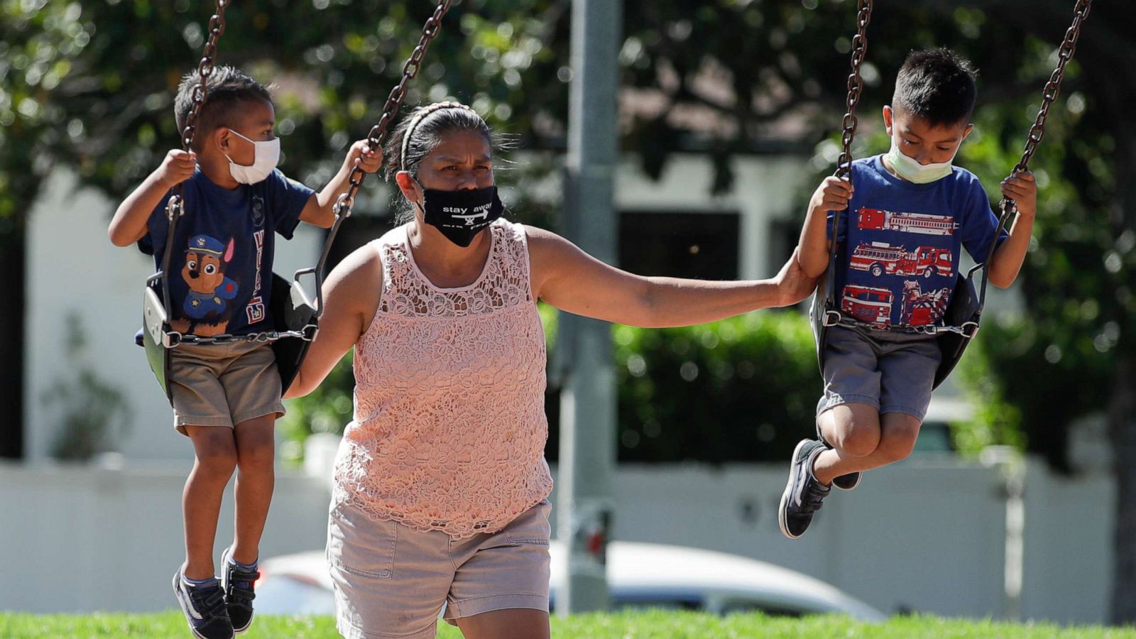 PHOTO: A woman and two children wear masks at a playground, July 11, 2020, in Los Angeles.