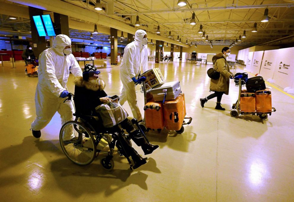 PHOTO: Workers wearing protective masks and suits help Chinese travellers leaving the arrival hall of RomeFiumicino International Airport, near Rome, Dec. 29, 2022 after being tested for the Covid-19 coronavirus.