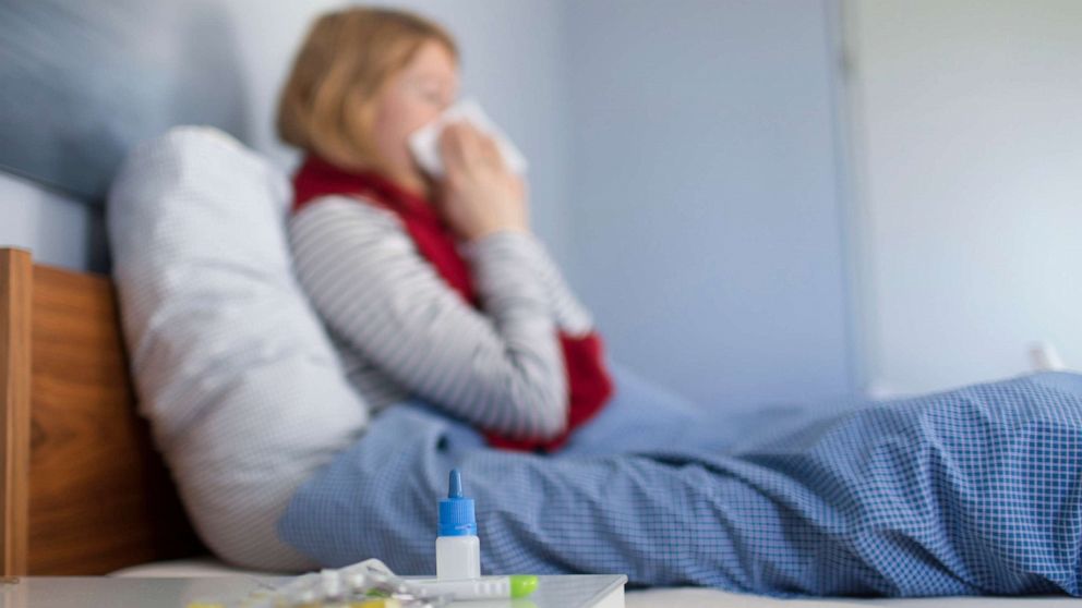 PHOTO: STOCK PHOTO: A sick woman sits in bed and blows her nose.
