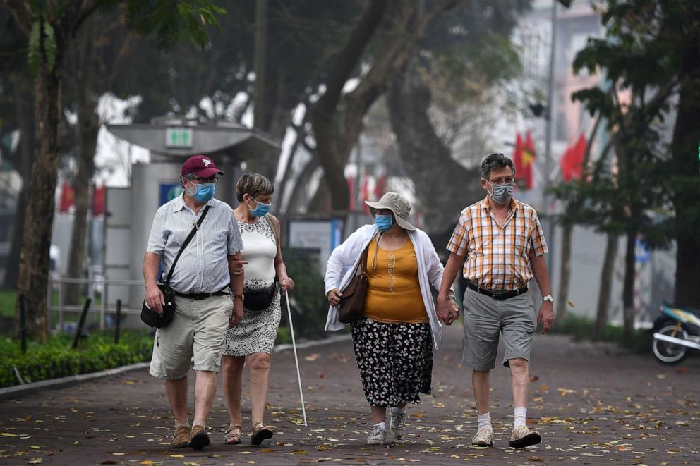 PHOTO: Tourists, wearing facemasks amid fears of the spread of the COVID-19 novel coronavirus, walk along the Hoan Kiem lake in Hanoi on March 16, 2020.