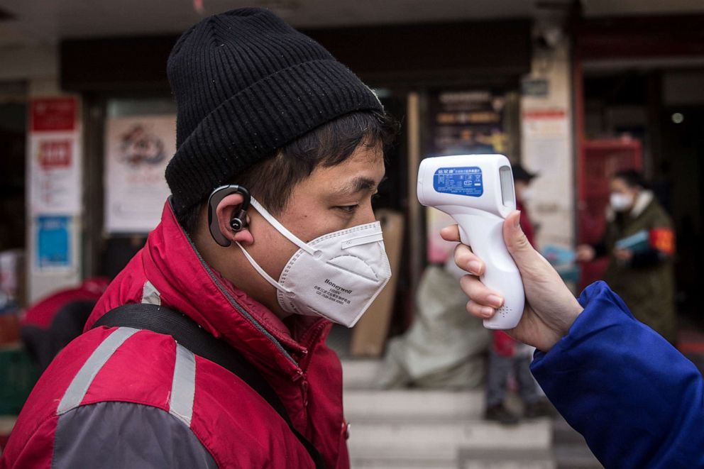 PHOTO: A community worker checks the temperature of courier in an Express station on January 29, 2020 in Hubei Province, Wuhan, China.