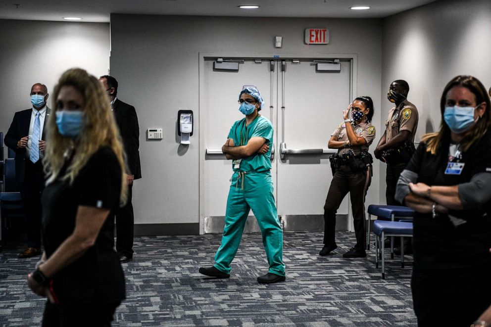 PHOTO: A doctor listens to the governor of Florida during a press conference to address the rise of coronavirus cases in the state, at Jackson Memorial Hospital in Miami, July 13, 2020.