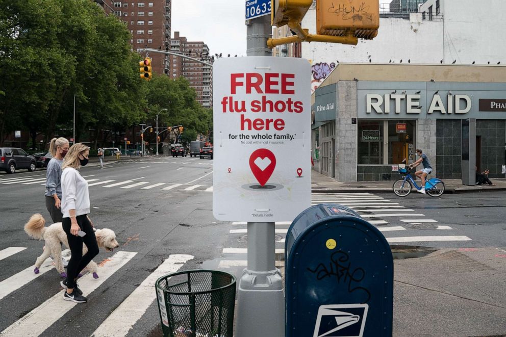 PHOTO: People walk past a free flu shot advertisement outside of a drugstore on Aug. 19, 2020, in New York.