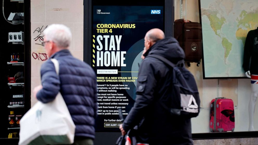 PHOTO: Pedestrians walk past a COVID-19 Tier 4 information sign in central London on Dec. 23, 2020.