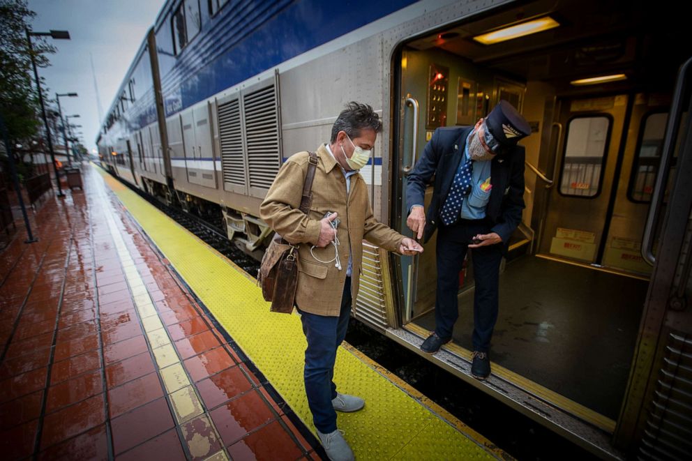 PHOTO: An Amtrak officer wearing a protective mask checks the ticket of a passenger at the Santa Ana Regional Transportation Center in Santa Ana, Calif., April 9, 2020.