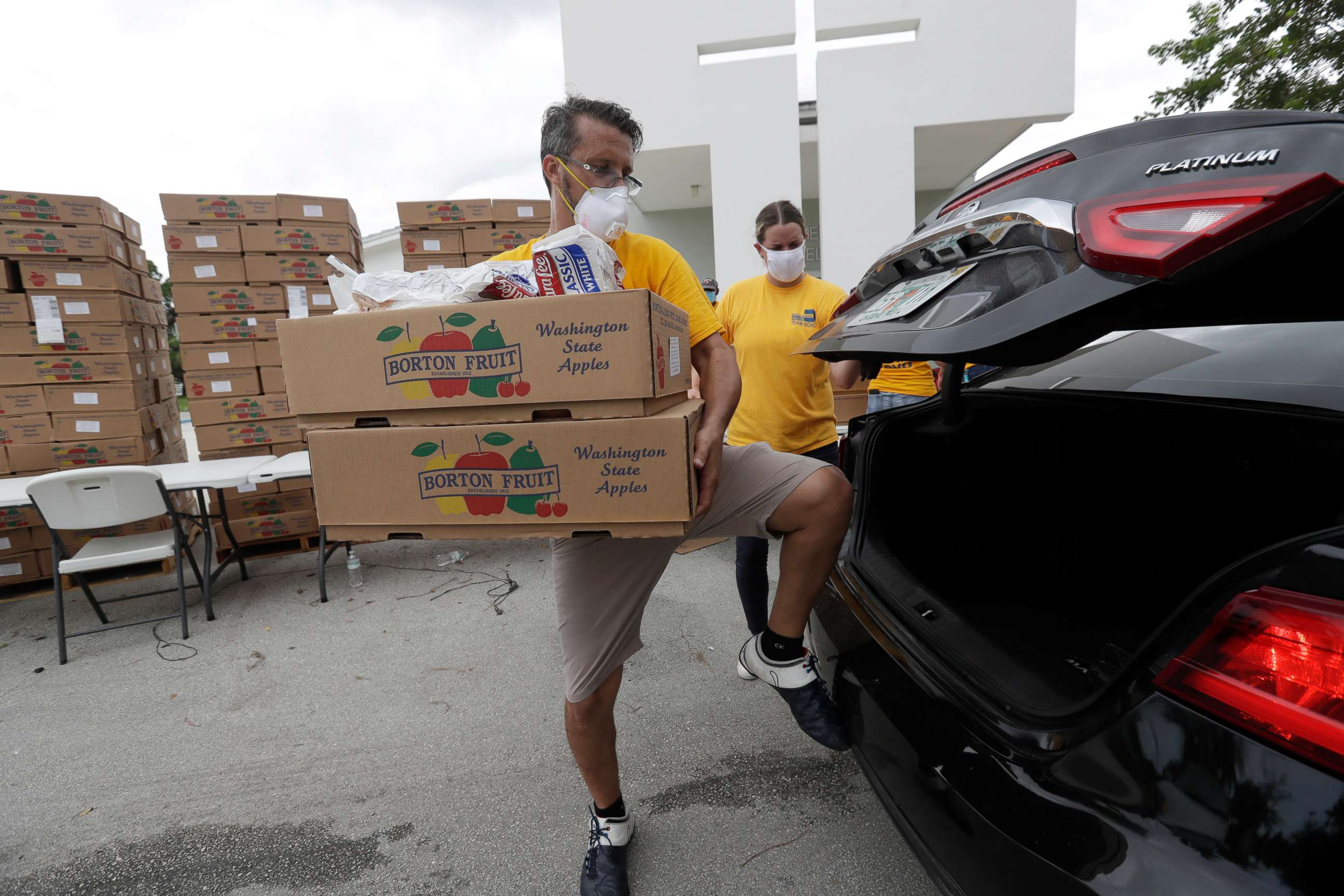 PHOTO: Oscar Amuz, with Volunteers in Action, loads groceries into cars during a food distribution event, July 21, 2020, at St. Monica's Catholic Church in Miami Gardens, Fla.