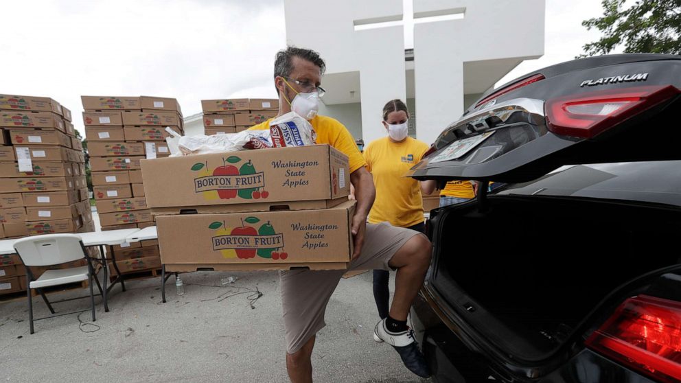 PHOTO: Oscar Amuz, with Volunteers in Action, loads groceries into cars during a food distribution event, July 21, 2020, at St. Monica's Catholic Church in Miami Gardens, Fla.