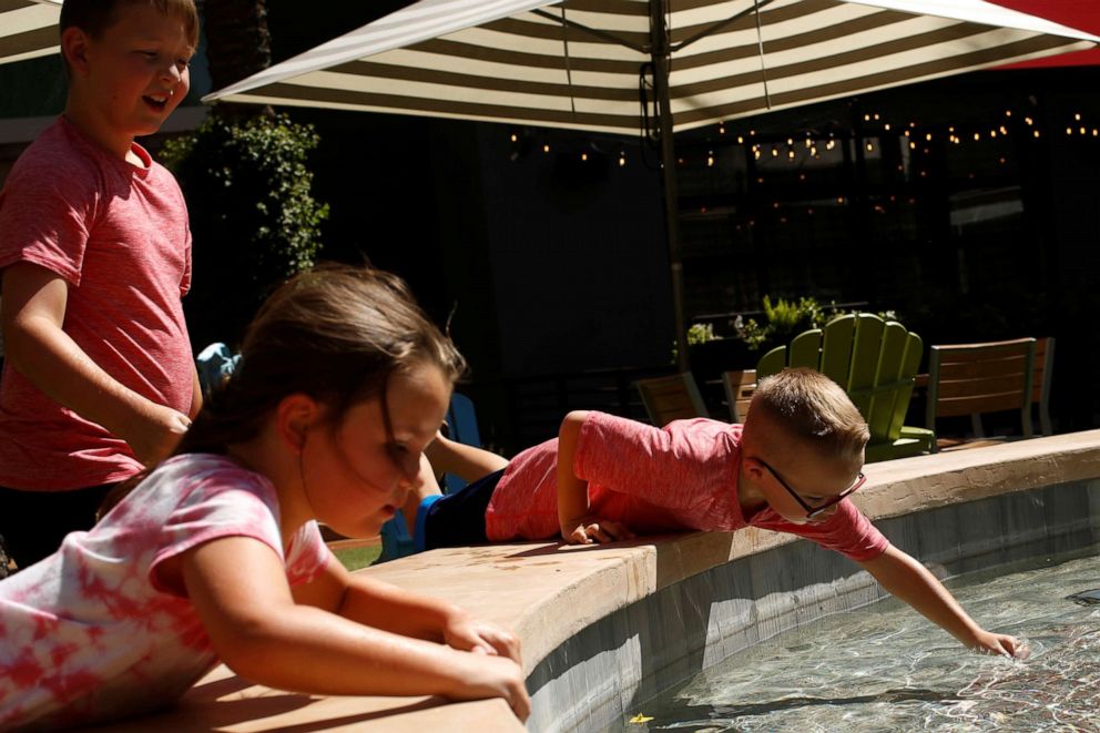 PHOTO: Children play with coins in a fountain on a hot day at Desert Ridge Marketplace during the phased reopening from coronavirus disease restrictions in north Phoenix, May 11, 2020.