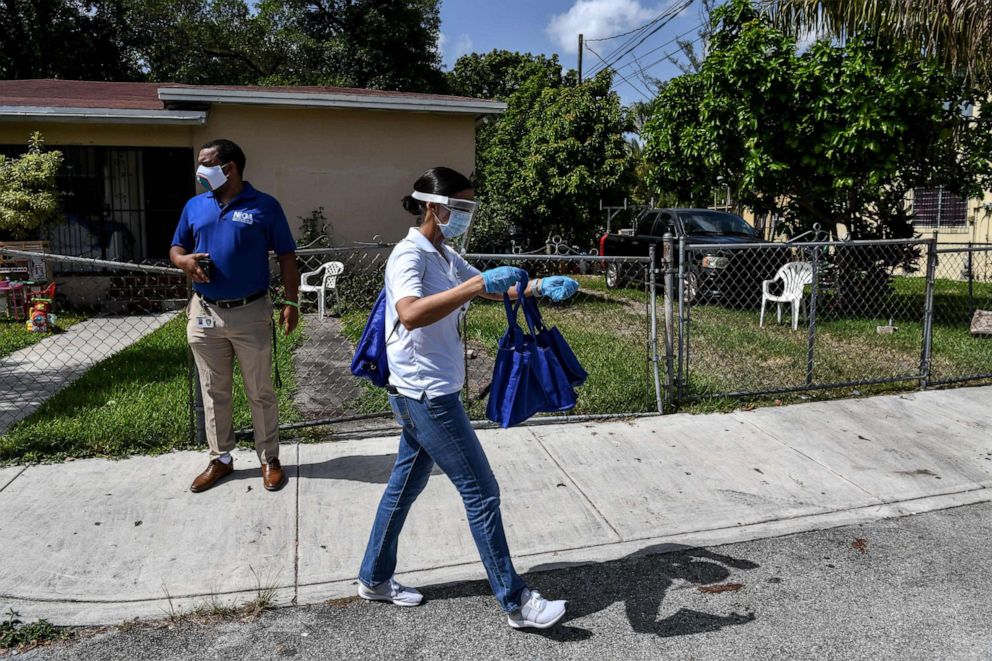 PHOTO: Catherimarty Burgos, a member of Miami-Dade County "surge teams" distributes bags with masks, sanitizers, and gloves to educate people on how to stay safe from COVID-19, in a neighborhood of Miami, on June 30, 2020.