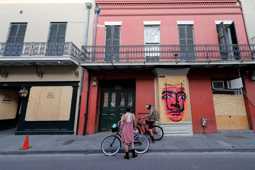 PHOTO: People on bicycles stop in front of shuttered businesses impacted by the coronavirus epidemic in the French Quarter of New Orleans, May 12, 2020.
