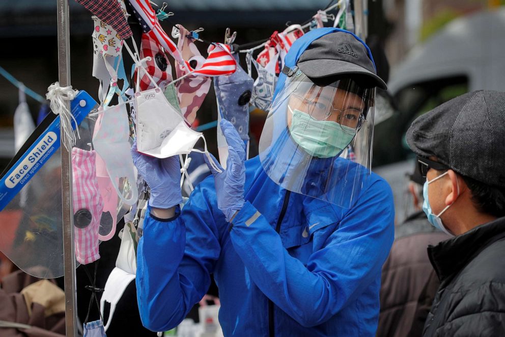 PHOTO: A man speaks to a street vendor about face masks, during the outbreak of the coronavirus disease, in the Queens borough of New York, May 19, 2020.