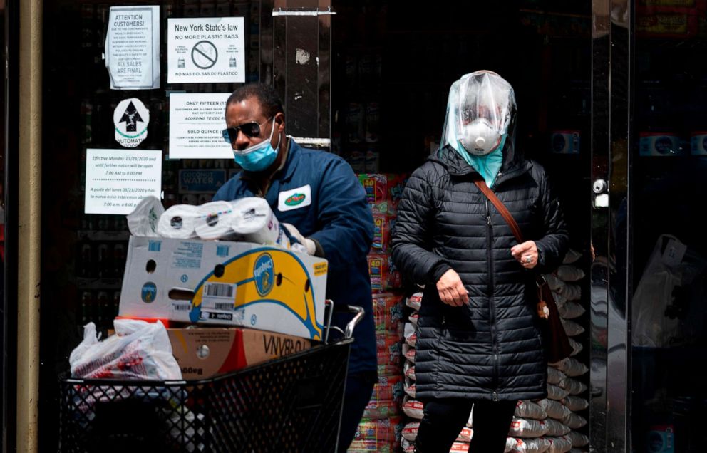 PHOTO: A woman wearing a mask comes out of a  grocery store in the Corona neighborhood of Queens on April 14, 2020, in New York.